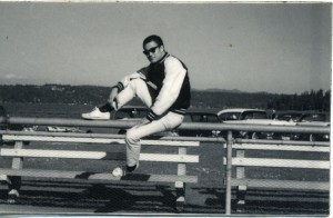 Bruce in sunglasses and varsity jacket on bleachers, Seattle, early years, looking cool as hell. Portrait. (Bruce Lee Family Archive)